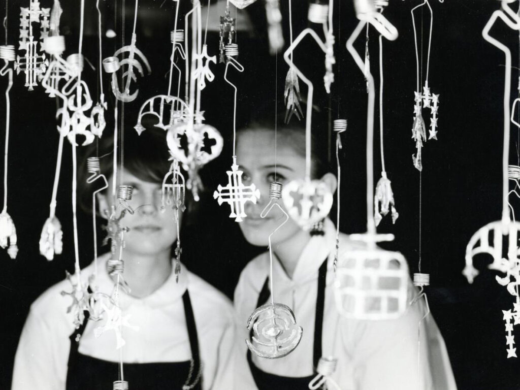 Kaksi naista katsoo roikkuvia kynttilänpidikkeitä.